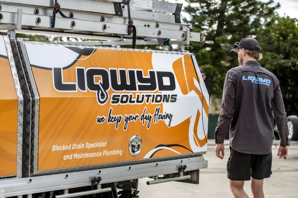 A man standing in front of a truck with a sign that says liqwyd solutions.